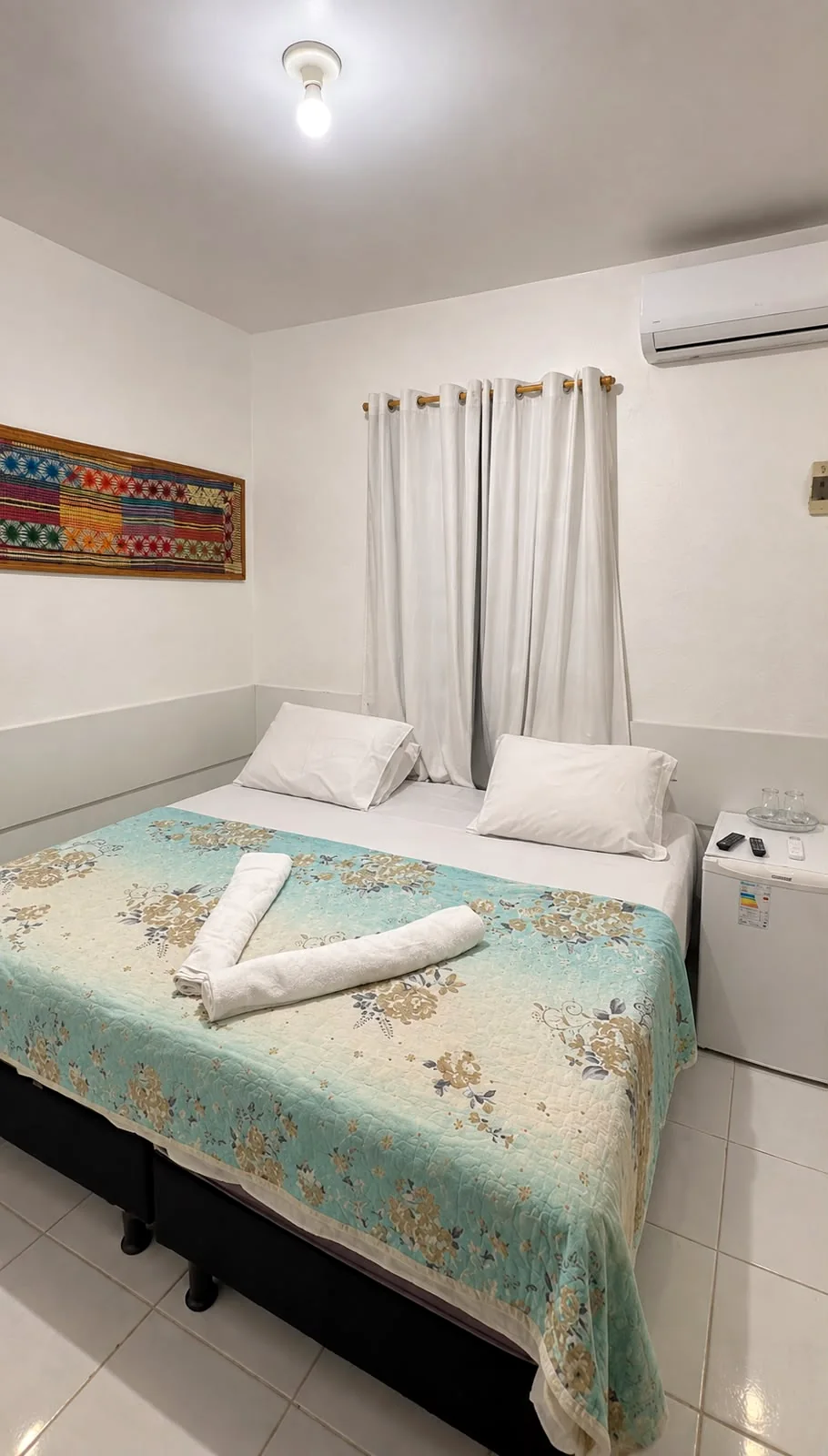 Quarto com cama de casal, enxoval estampado e ar-condicionado